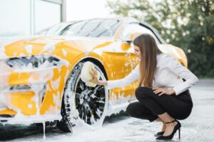 Attractive woman wearing business look washing wheel, car rims