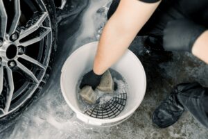 Car wash and detailing concept. Top view of washing tools in car wash service, white bucket with