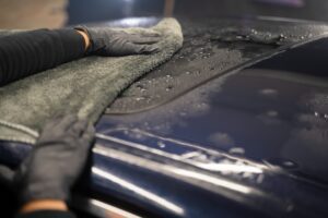 Car wash worker wipes the car after washing with microfiber towel. Professional car wash