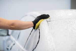 Man washing a soapy black car in a cleaning and detailing service