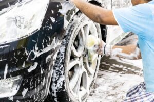 Worker wipe clean car using detergent soap foam with cloth
